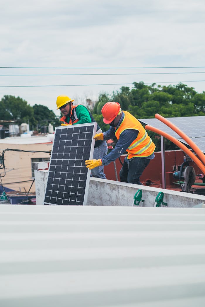 services-03 Two workers in safety gear installing solar panels on a rooftop for sustainable energy.
